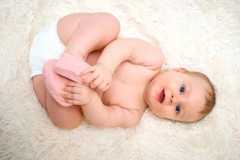 A small child is lying on his back and holding on to the legs Stock Photos