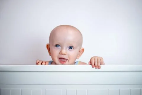 A small child peeks out on a white background. The child looks out of bed. peek Stock Photos