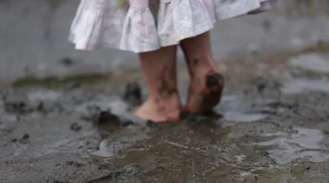SMALL CHILD PLAYING AND JUMPING IN MUD Stock Footage 53129981