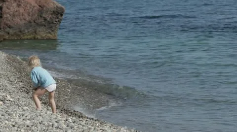 A small child playing on the beach. Video stock 22156576