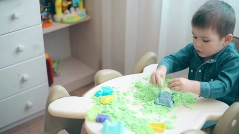 A small child is playing with kinetic sand and develops motor skills of hands Video stock 88548558