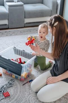 Small child playing with toy container under mother supervision, early chil.. 写真素材
