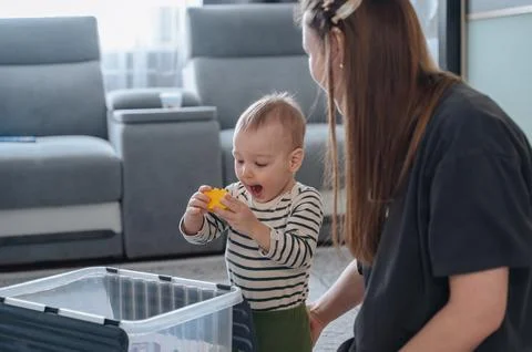Small child playing with toy container under mother supervision, early chil.. 写真素材