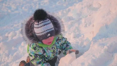 A small child is playing in a winter Park with snow. A Sunny winter day. Fun and Vidéo 85058141