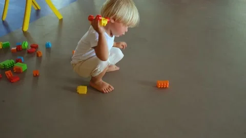 A small child plays with a construction set and a toy car on the floor Stock Footage 194777495
