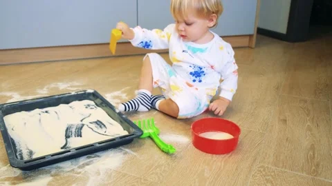 A small child plays with flour in the kitchen takes flour with a shovel as if in Stock Footage 201458977