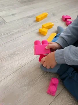 A small child plays with large plastic building blocks on the floor Stock Photos