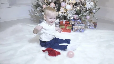 A small child plays a New Year toy near the Christmas tree Stock Footage 75243958