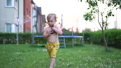Small child plays with a professional video camera in the backyard. Hobbies and Stock Footage 156043796