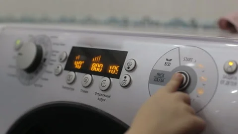 A small child presses a button on a panel of a washing machine. The concept of Stock Footage 120385924