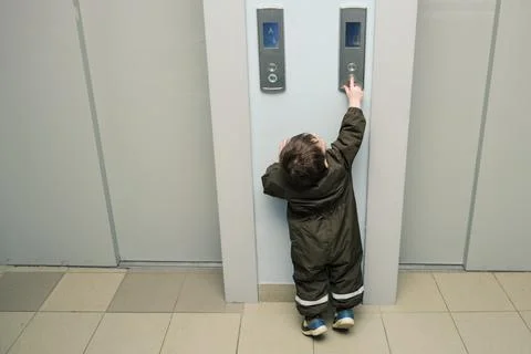 A small child presses the elevator call button. Baby reaches for the elevator Foto stock