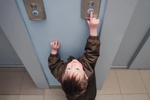 A small child presses the elevator call button. Baby reaches for the elevator Foto stock