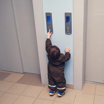 A small child presses the elevator call button. Baby reaches for the elevator Foto stock