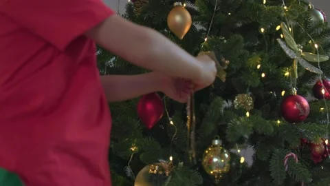 Small child red Santa hat decorates Christmas tree beautiful bright balls Stock-Footage 220917524