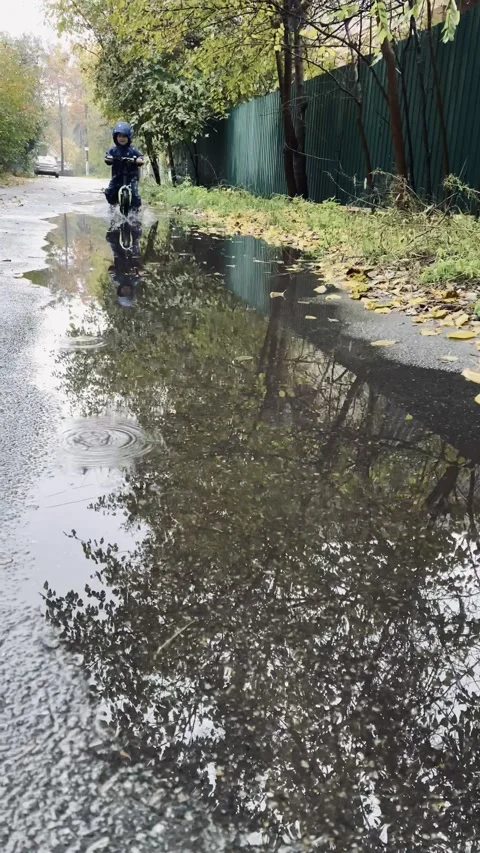 A small child rides a bicycle through puddles. Stock Footage 142797496