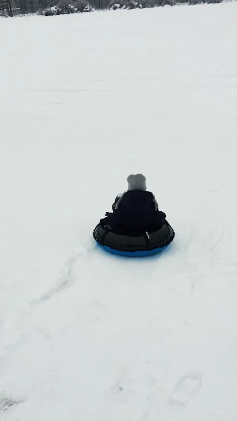 A small child rides a inflatable snow tube from a snowy mountain. Stock Footage 165239028