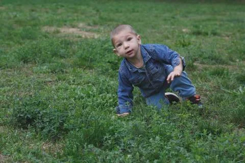 Small child is risign with one hand from the grass Stock Photos