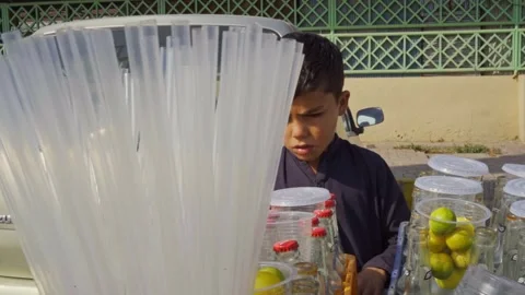 Small child running a roadside cart selling fresh lemon soda to passersby in a Stock Footage 293472224