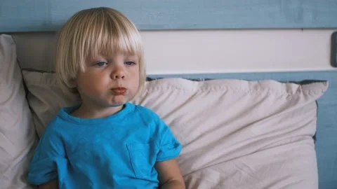 A small child sits on the bed and eats a carrot Stock Footage 220731915