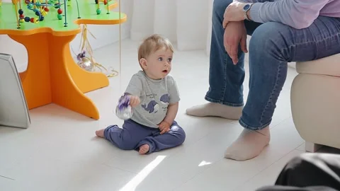 A small child sits on the floor next to his parents and plays Stock Footage 154370996