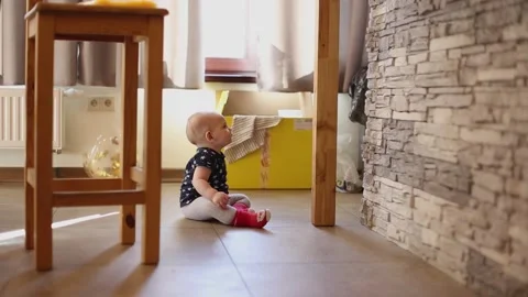 A small child sits on the floor of the room and begins to quickly crawl towards Stock Footage 150885864