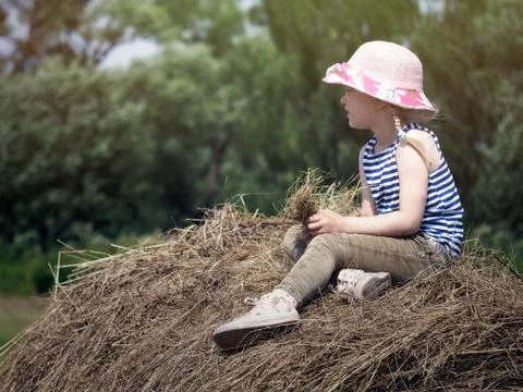 A small child sits on a haystack. Stock Photos