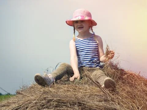 A small child sits on a haystack. Stock Photos