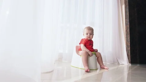 Small child sits on the potty and relieves itself Stock Footage 72433778