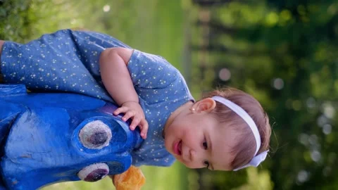 A small child sits on a swing in the playground, eats an orange, the use of vita Vídeo Stock 245361489