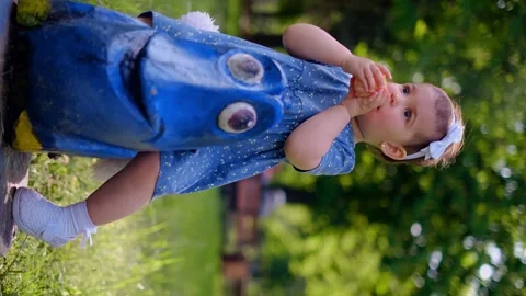 A small child sits on a swing in the playground, eats an orange, the use of vita Stock Footage 245361534