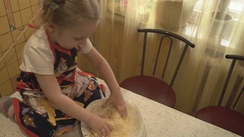 A Small Child Sits on the Table and Knead the Dough Video stock 74135926