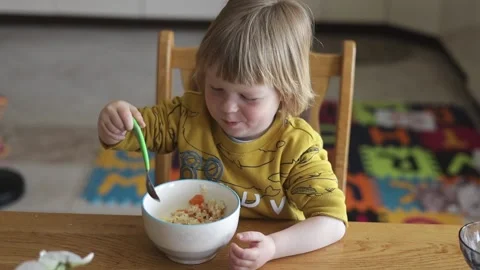 A small child sits at the table and eats organic food from a plate. Stock Footage 239641627