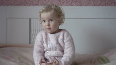 A small child is sitting on the bed and talking emotionally Stock Footage 344843817
