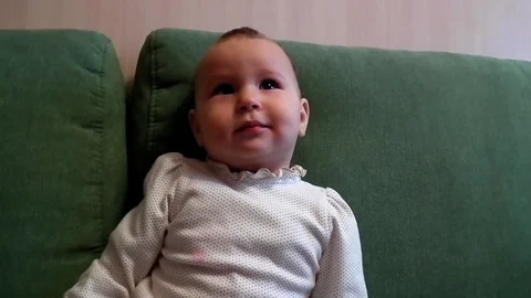 A small child is sitting on the couch and smiling Stock Footage 86317326