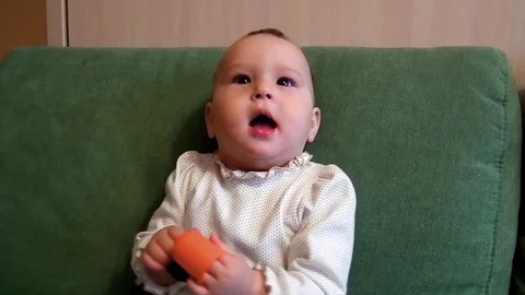 A small child is sitting on the couch and smiling Stock Footage 86317361