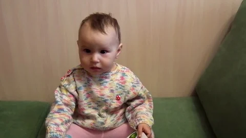 A small child is sitting on the couch and smiling Stock Footage 87834974