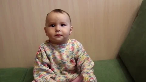 A small child is sitting on the couch and smiling Stock Footage 87835011