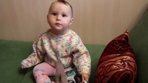 A small child is sitting on the couch and smiling Stock Footage 87835047