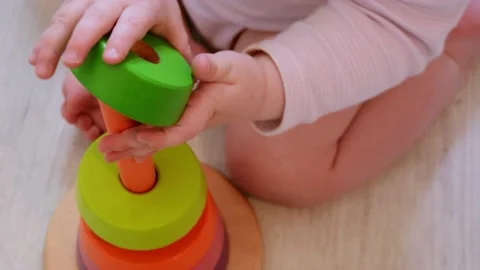 Small child sitting on the floor and building wooden pyramid toy Stock Footage 207684515