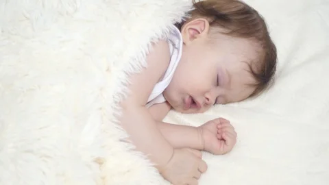 Small child is sleeping in his crib covered with a white blanket. closeup Stock Footage 96087963