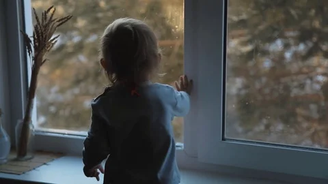 Small child standing at the window and enjoy the sunrise frosty morning. Stock Footage 72618615