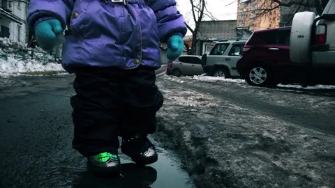 Small child steps into a puddle 4k video Stock Footage 148210780