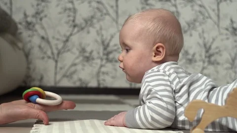 Small child in striped bodice is given toy and the girl begins to play it. Stock Footage 127462642