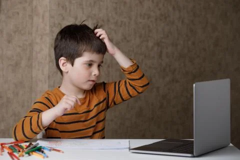 A small child is studying at the computer. Distance learning at home quarantine Stock Photos