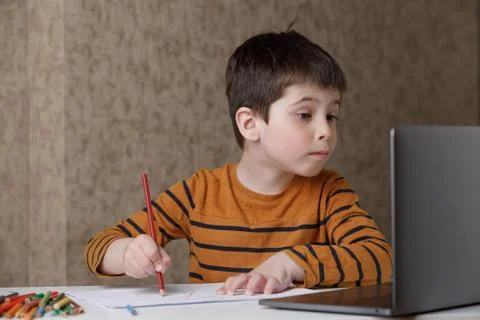 A small child is studying at the computer. Distance learning at home quarantine Stock Photos