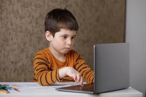 A small child is studying at the computer. Distance learning at home quarantine Stock Photos
