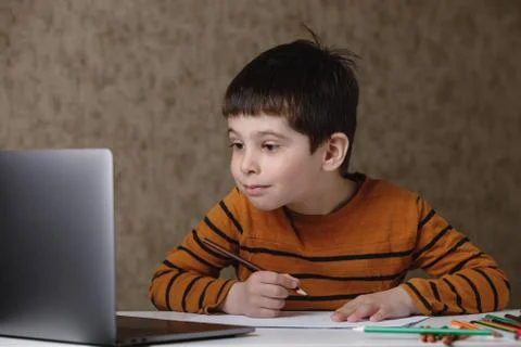 A small child is studying at the computer. Distance learning at home quarantine Stock Photos