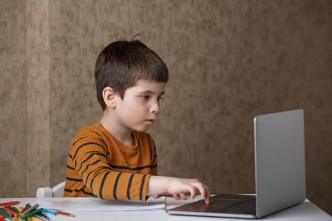 A small child is studying at the computer. Distance learning at home quarantine Stock Photos
