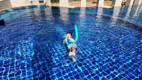 Small child in swimming pool with floating foam stick. S Stockbeeldmateriaal 267645185