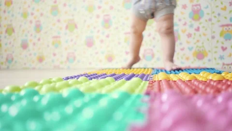 A small child takes his first steps on an orthopedic Mat Stock Footage 76604414